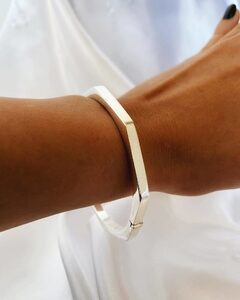 a person wearing a white shirt and a silver bracelet.